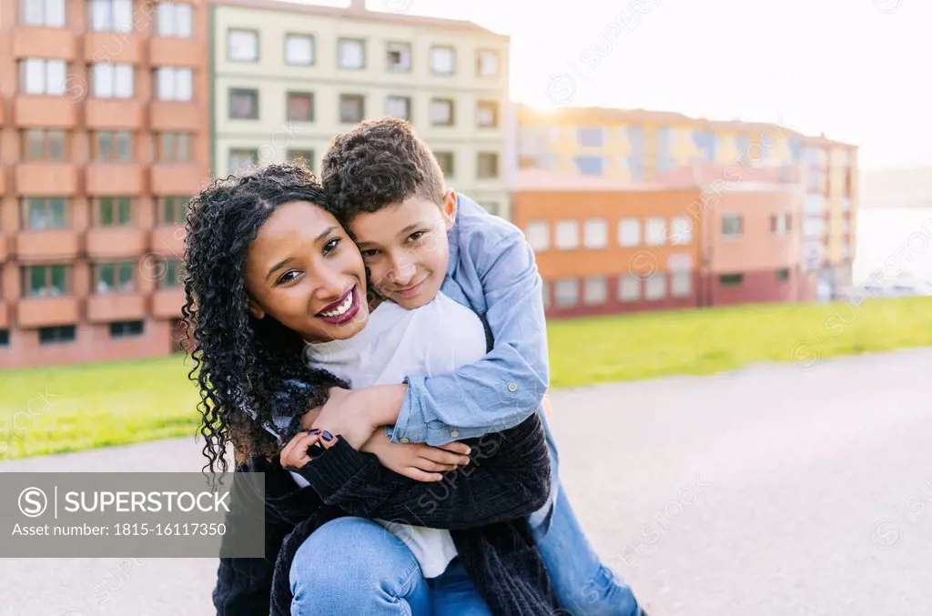 Portrait of happy boy hugging his mother outdoors
