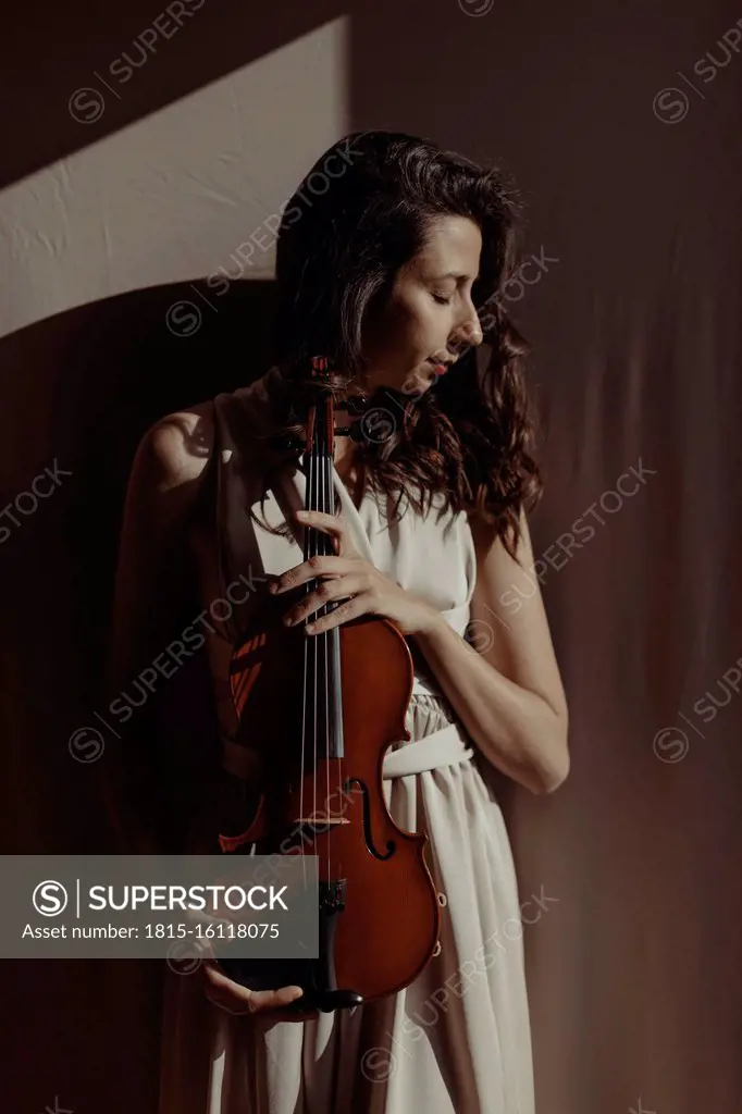 Woman holding violin with closed eyes