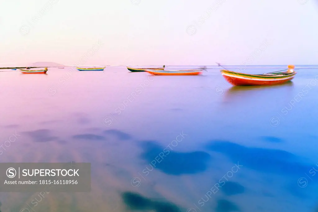 Fishing boats floating on the water of the Atlantic sea at sunset, Jericoacoara, Brazil
