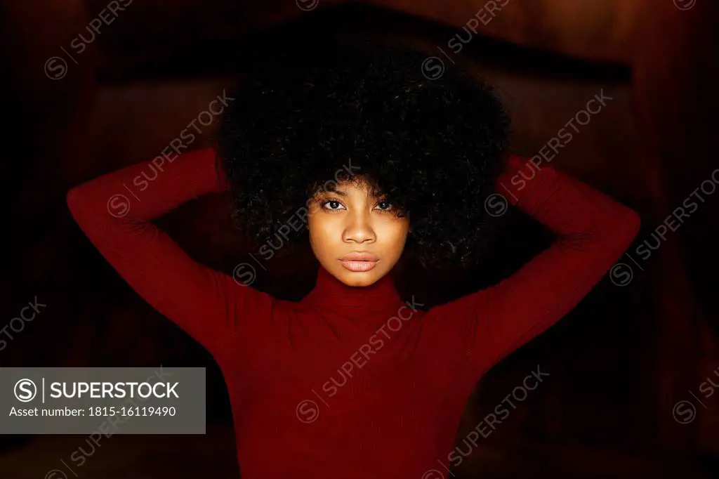 Portrait of young woman in red bodysuit, hands in hair