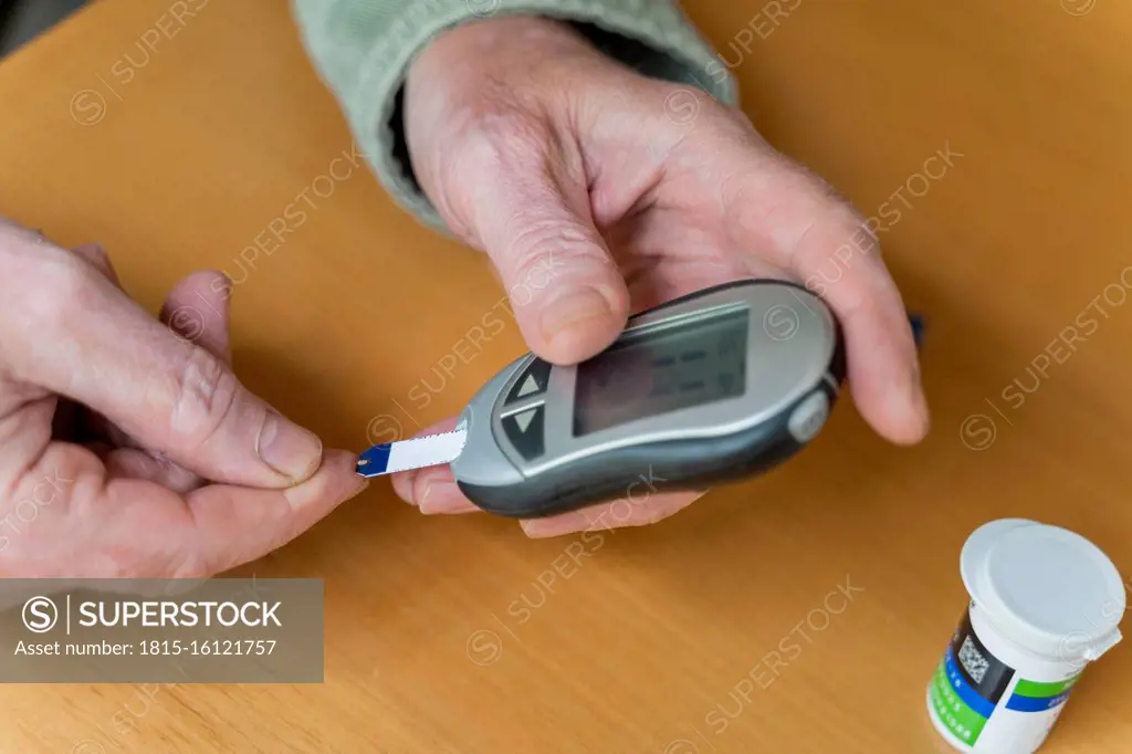 Cropped hands of glaucometer while examining blood sugar test at home