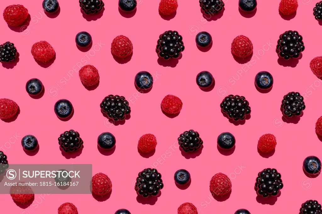 Pattern of raspberries, blueberries and blackberries against pink background