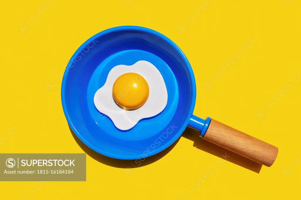 Illustration of fried egg on blue pan against yellow background