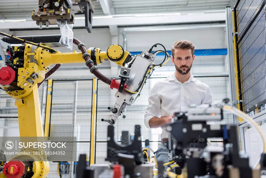Confident male robotics expert looking at machinery in automated industry