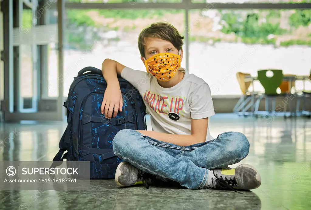 Boy sitting on the floor in school wearing mask