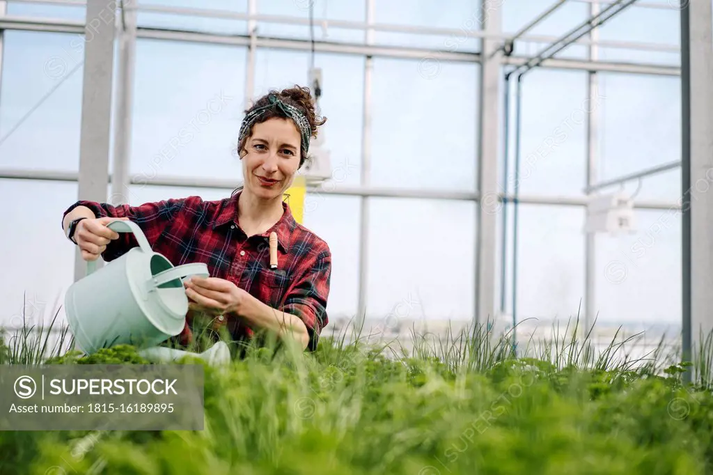 Woman watering plants in greenhouse of a gardening shop