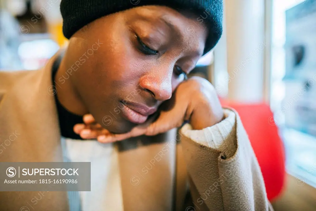 Pensive young woman with hand on chin in coffee shop