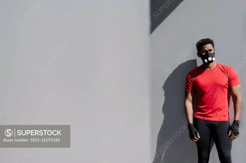 Sportsman wearing face mask standing at grey wall