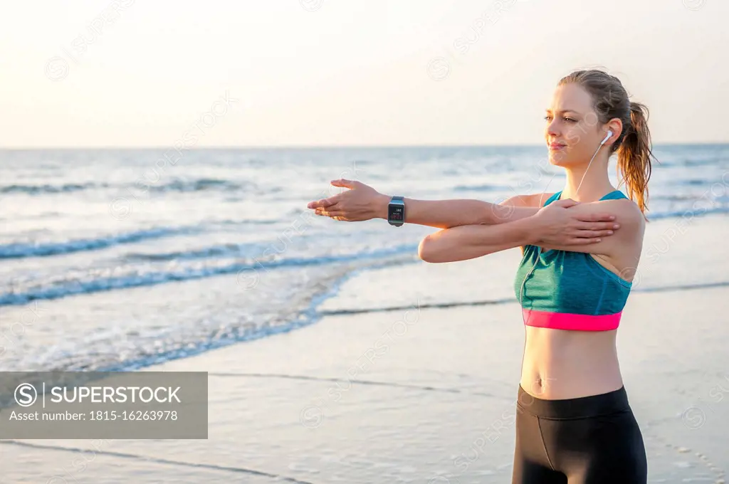 Sporty woman stretching at the sea at sunrise, Gran Canaria, Spain