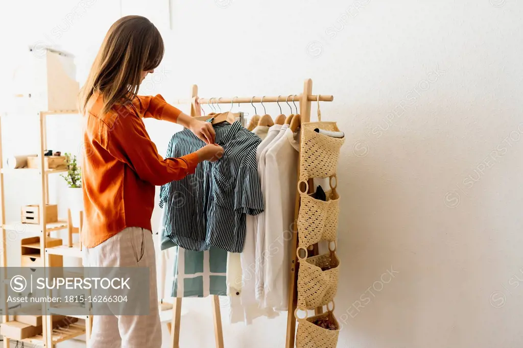 Female fashion designer working at home with clothes stand