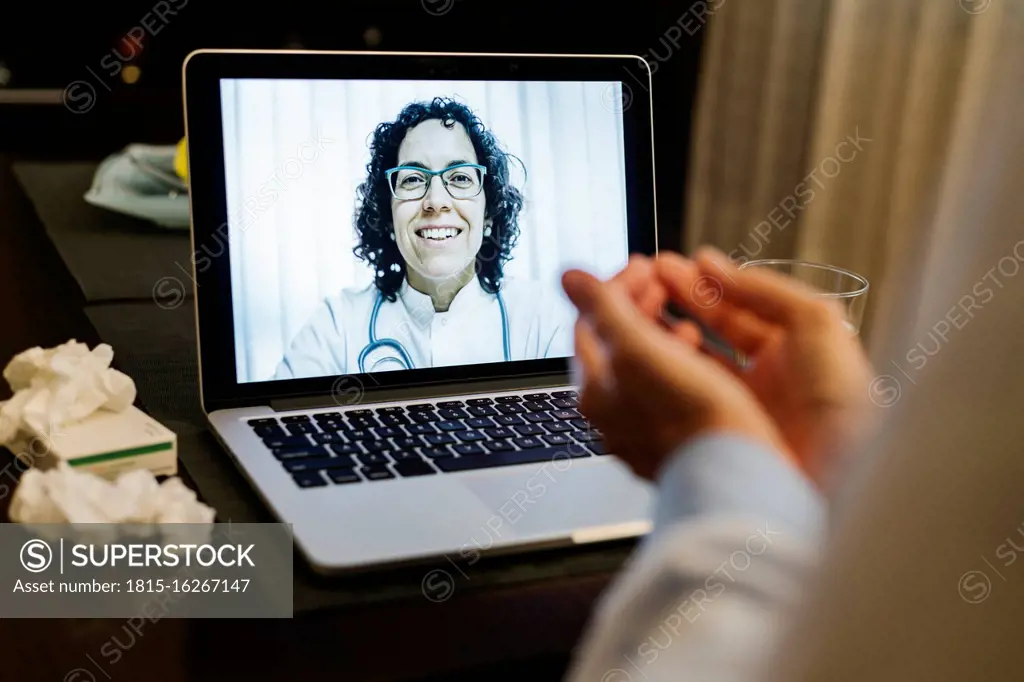 Retired senior ill woman discussing over video call with smiling doctor at home