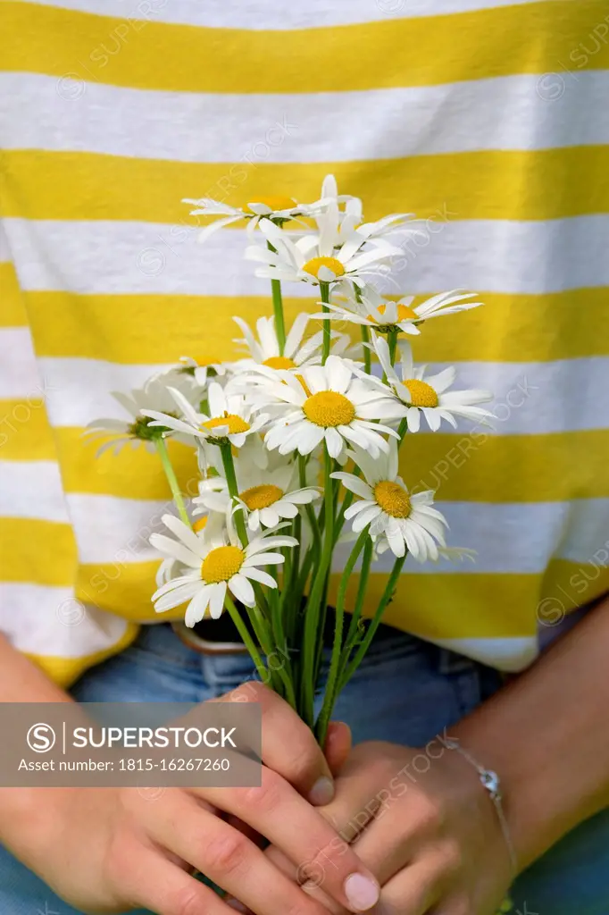 Close-up of young woman holding oxeye daisies in park