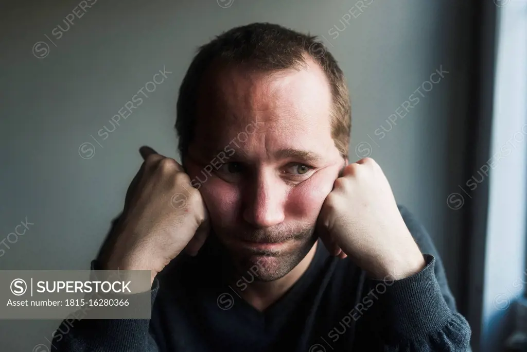 Close-up of sad mid adult man with head in hands against wall at home