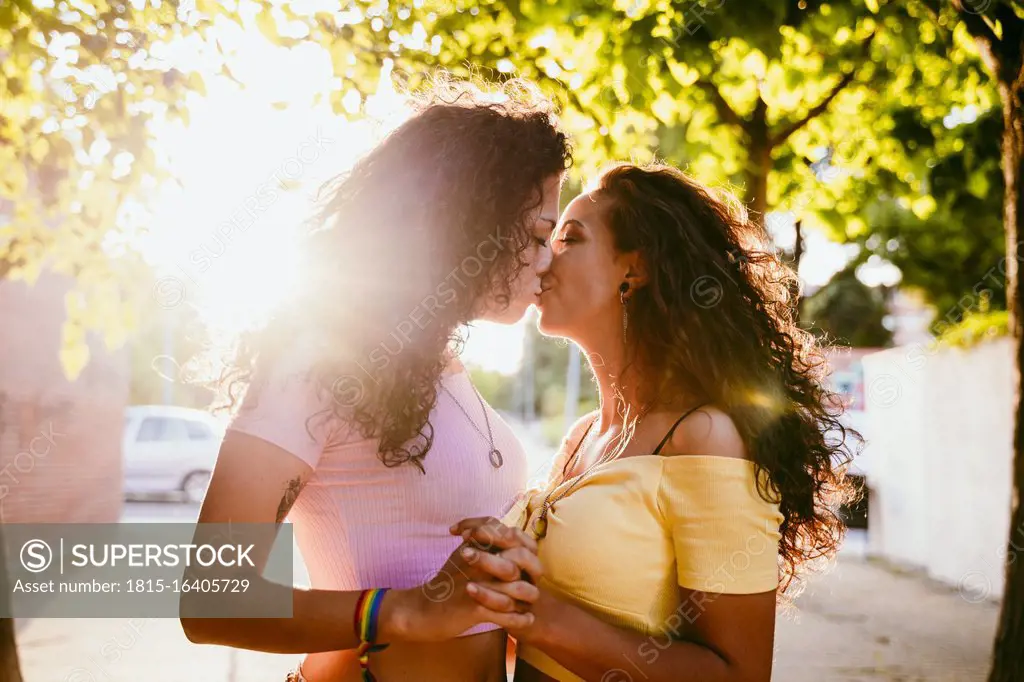 Romantic lesbians kissing while standing in city on sunny day