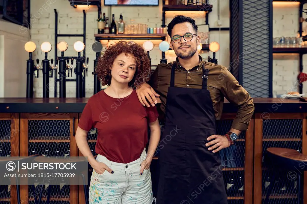 Portrait of confident owner couple at the counter in a pub