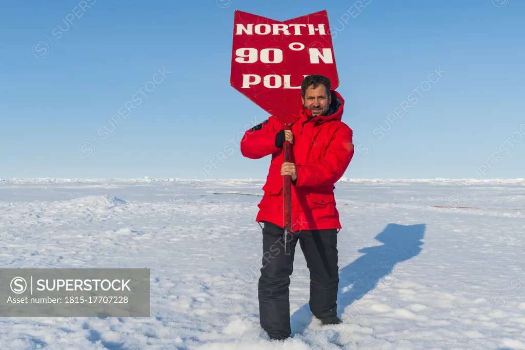 Portrait of man posing with sign on North Pole