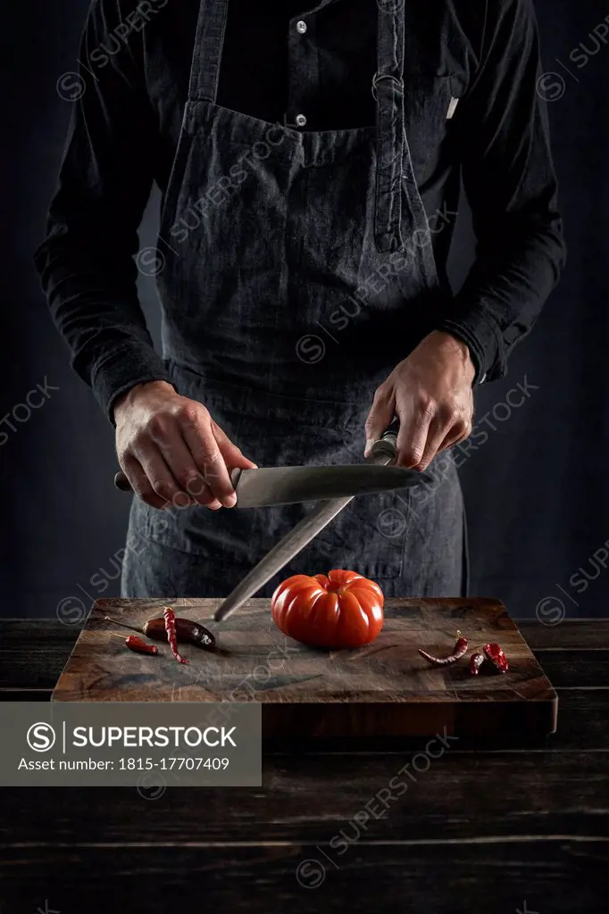 Man sharping knife while standing at table