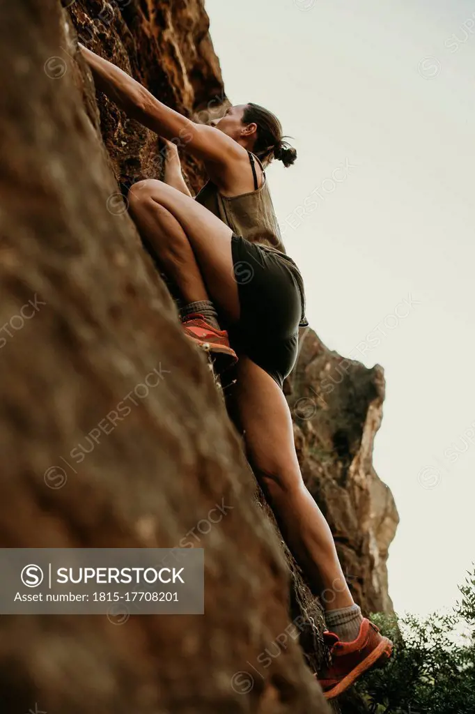 Determinant woman climbing rock mountain in forest