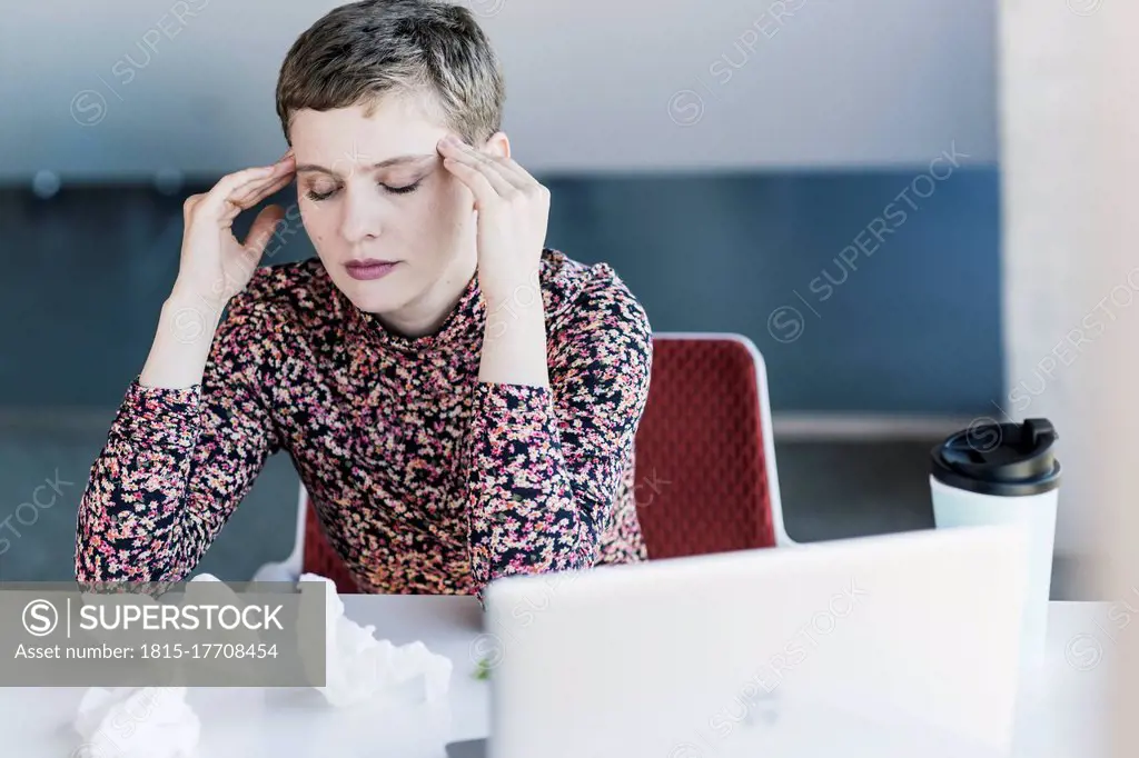 Businesswoman at desk in office having headaches