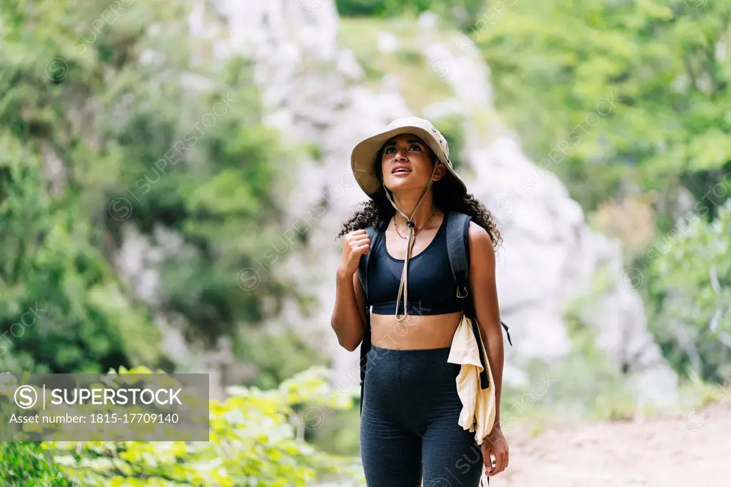 Young woman wearing hat hiking on mountain at Ruta Del Cares, Asturias, Spain
