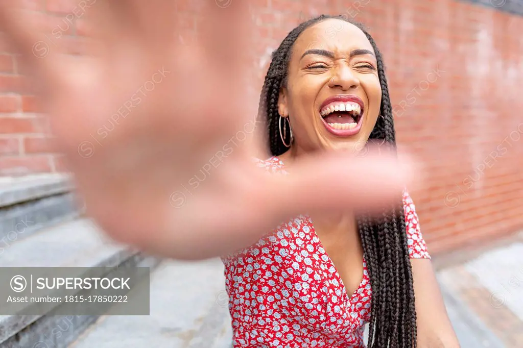 Woman showing stop gesture while sitting on staircase in city