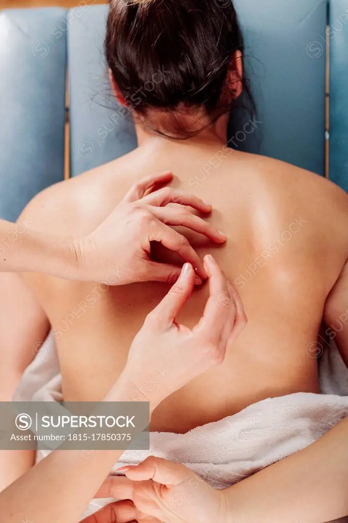 Physiotherapist inserting needle on woman back lying on table