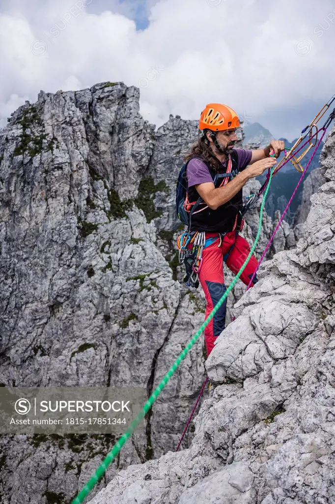 Mature man with ropes standing on mountain, European Alps, Lecco, Italy