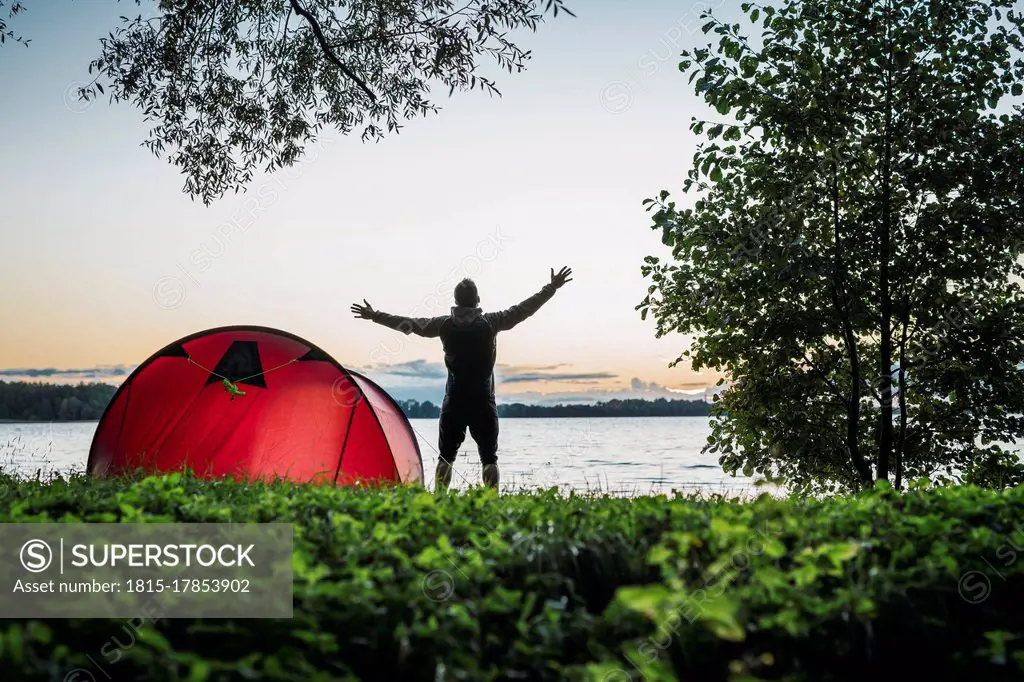 Man camping in Estonia, stretching at lake