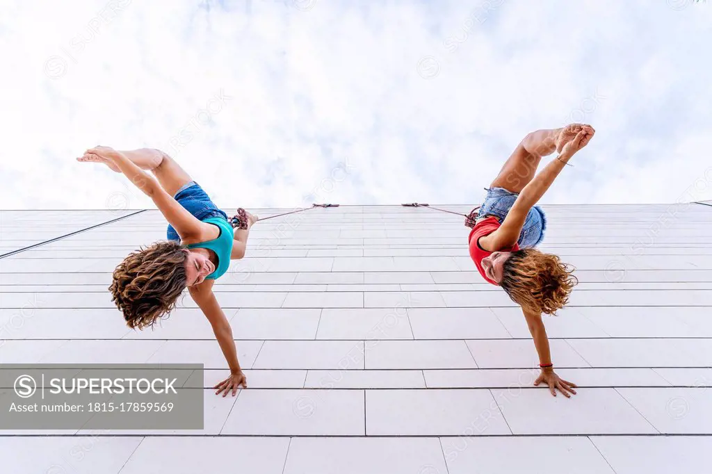 Aerial dancers touching toes while hanging on window
