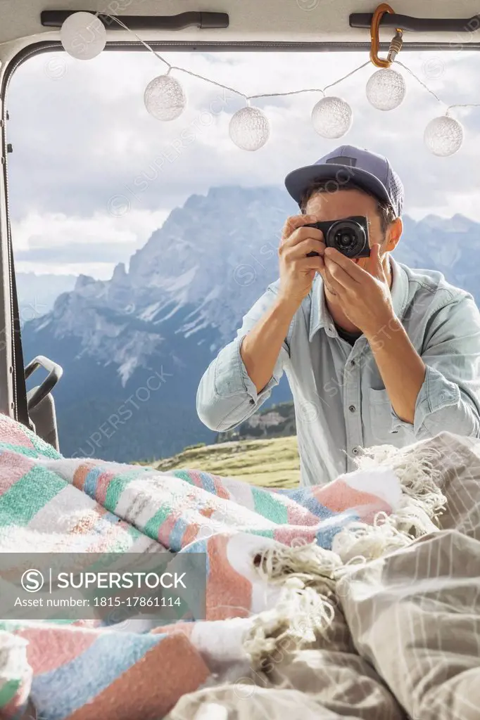 Male tourist photographing interior of campervan against mountains, Sesto Dolomites, Dolomites, Alto Adige, Italy
