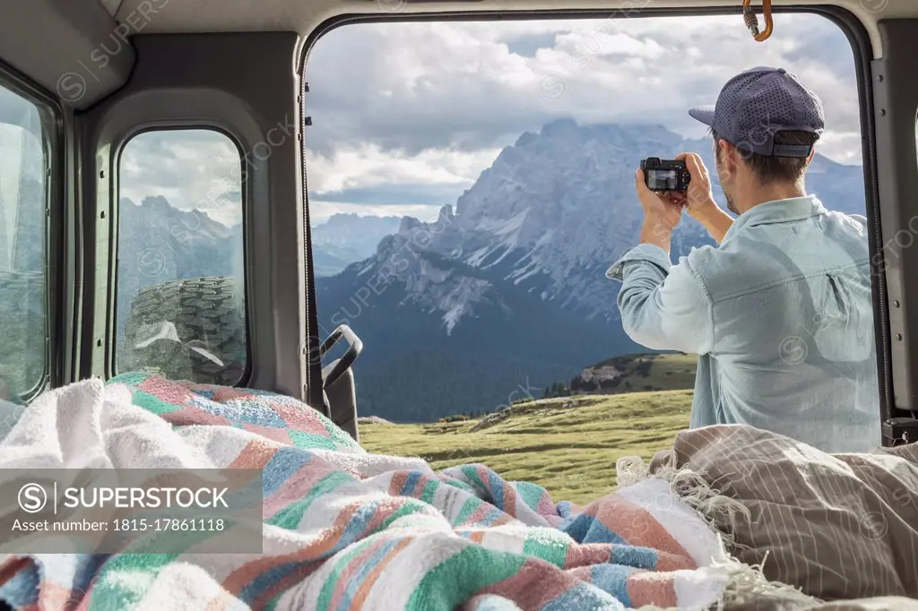 Man photographing scenic mountain ranges while standing by campervan. Sesto Dolomites, Dolomites, Alto Adige, Italy