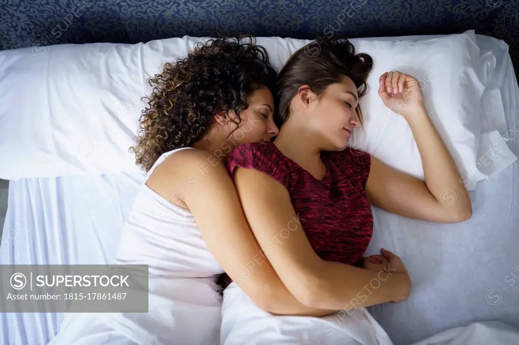 Lesbian couple sleeping on bed at home