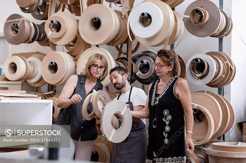 Interior designer and carpenter choosing spool while standing at workshop