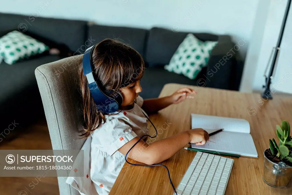 Female preschooler wearing headphones at desk