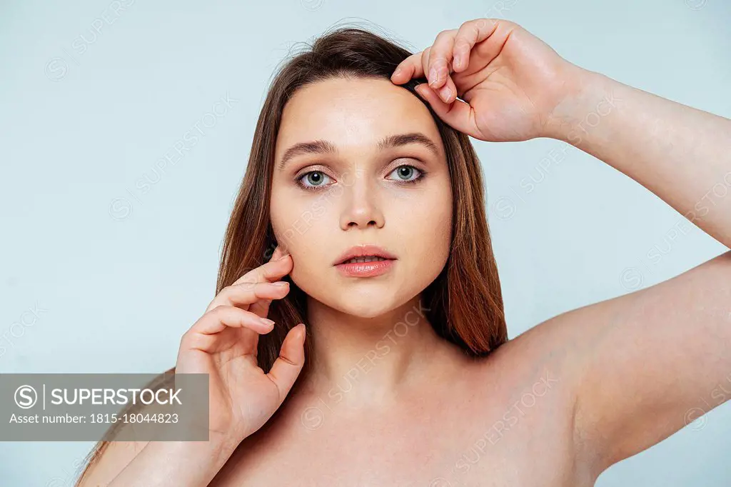 Young woman staring while standing against white background