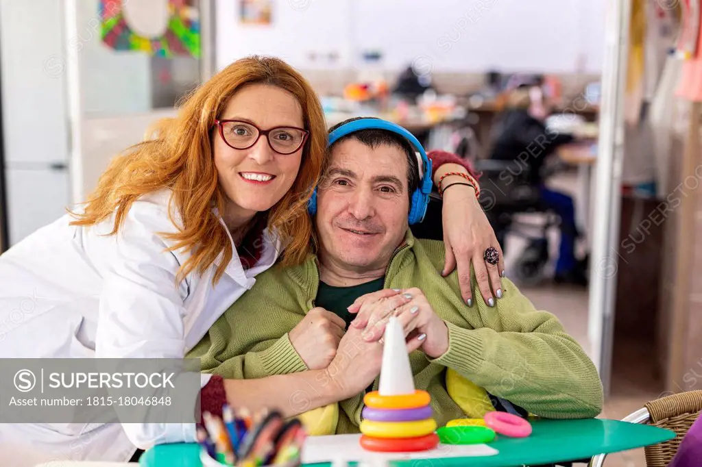 Happy female caregiver with disabled man in nursing home