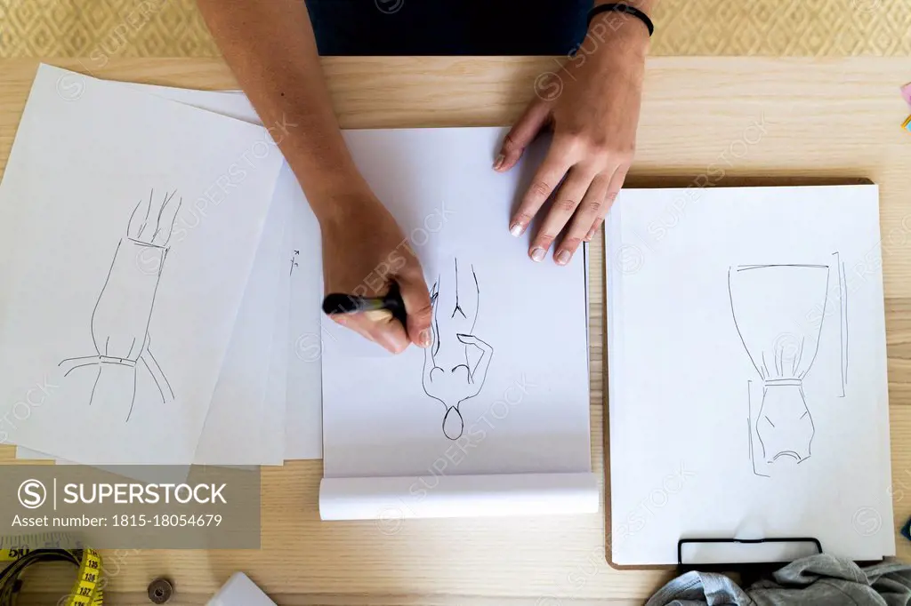 Female designer's hand drawing sketch in book at studio
