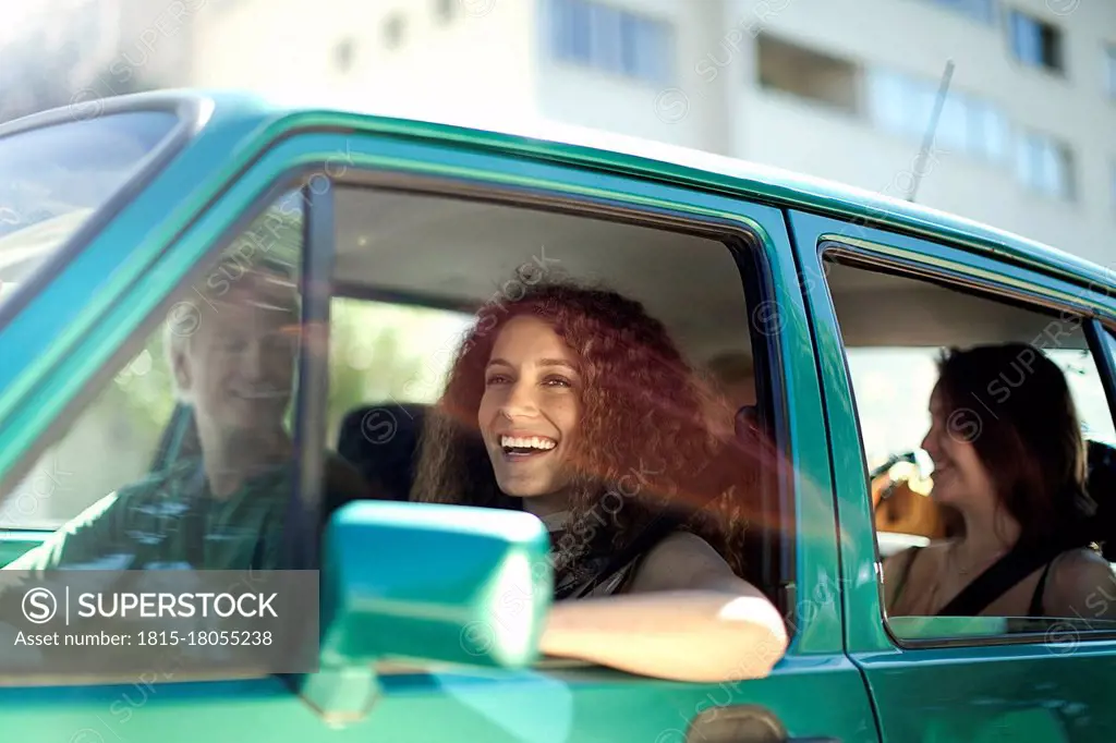 Smiling woman looking away while sitting with friends in car