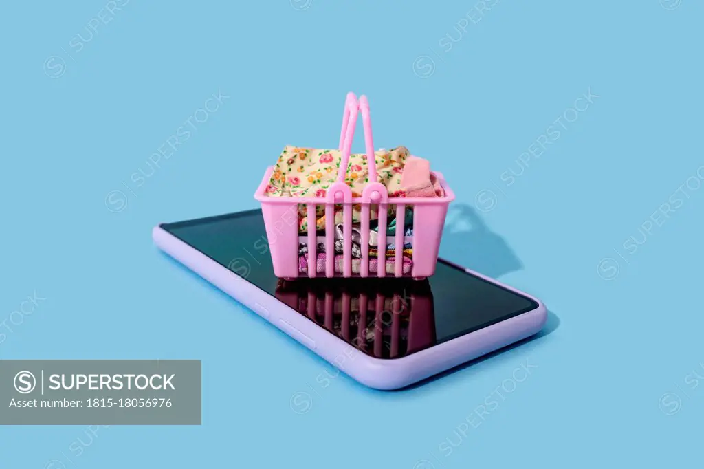 Miniature shopping basket lying on top of smart phone