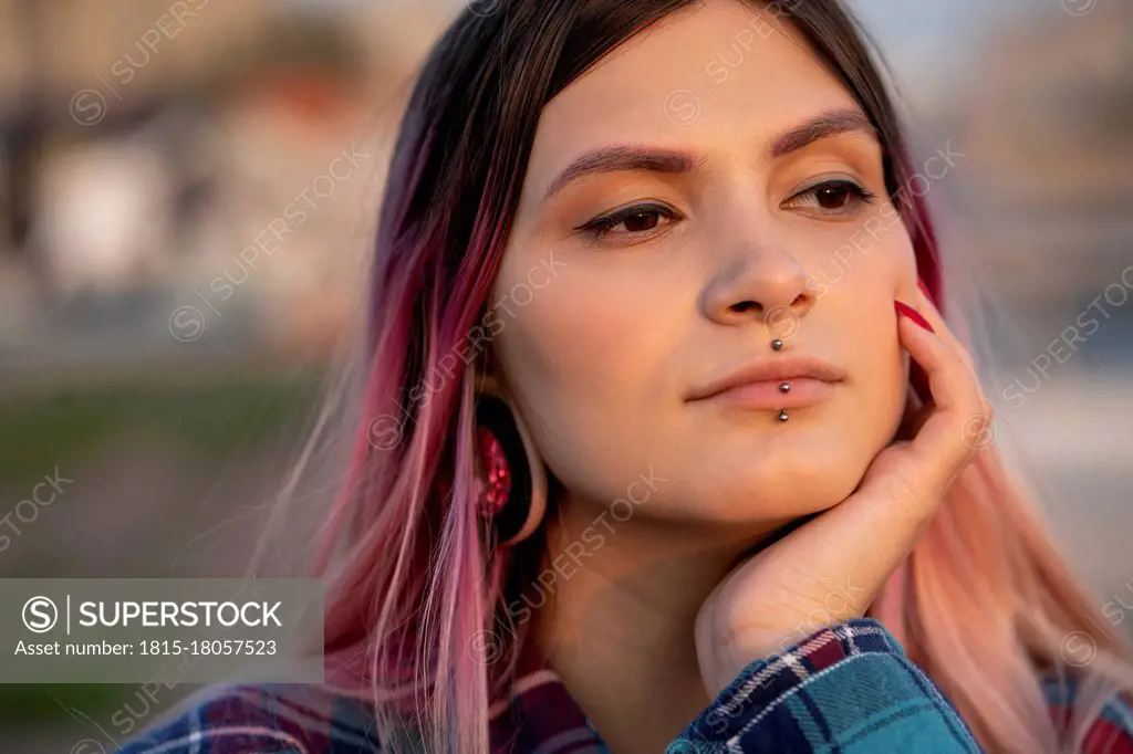 Hipster woman with hand on chin day dreaming outdoors