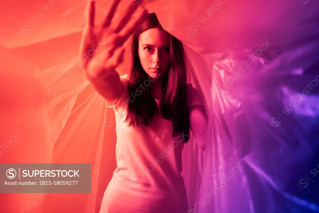 Young woman doing stop gesture while covered in plastic during coronavirus