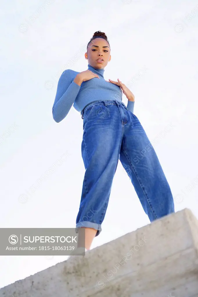 Young woman staring while standing on retaining wall