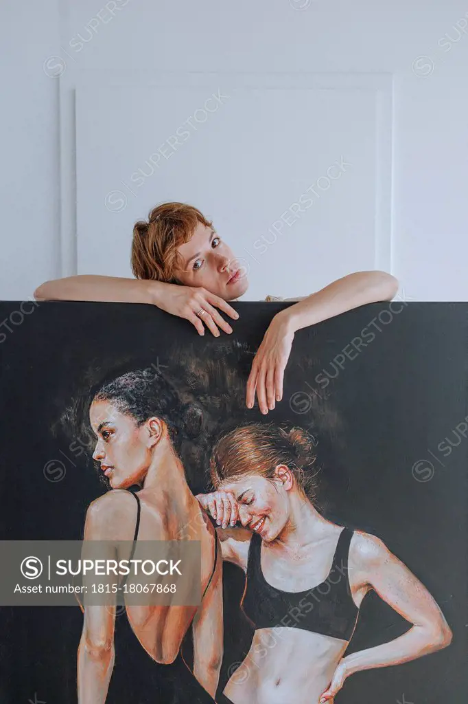 Mid adult female artist standing behind painting in studio