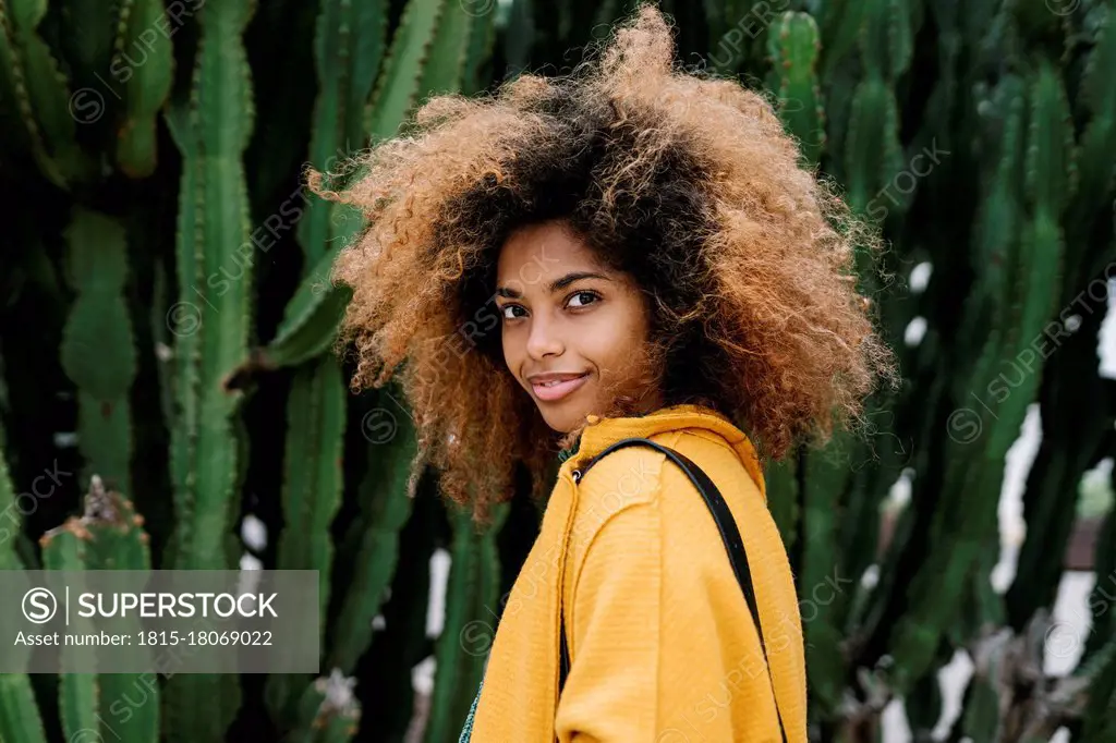 Smiling Afro woman standing by cactus in background