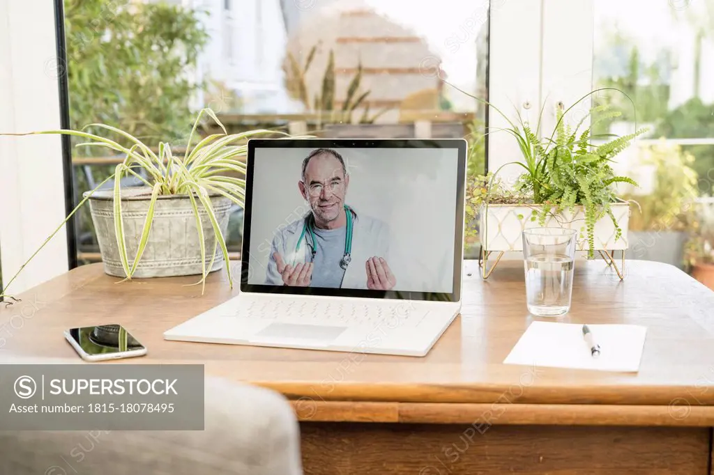 Smiling doctor on video call through laptop at home