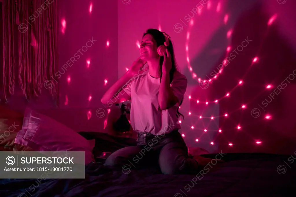 Young woman enjoying music in bedroom at home
