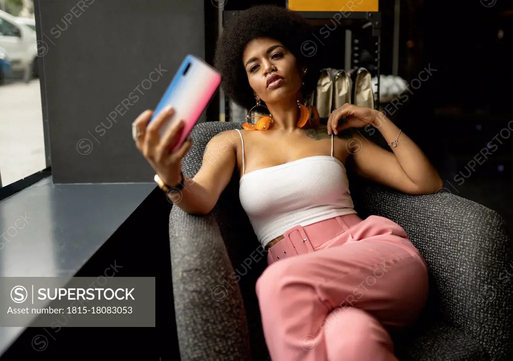 Young woman taking selfie on smart phone while sitting at cafe