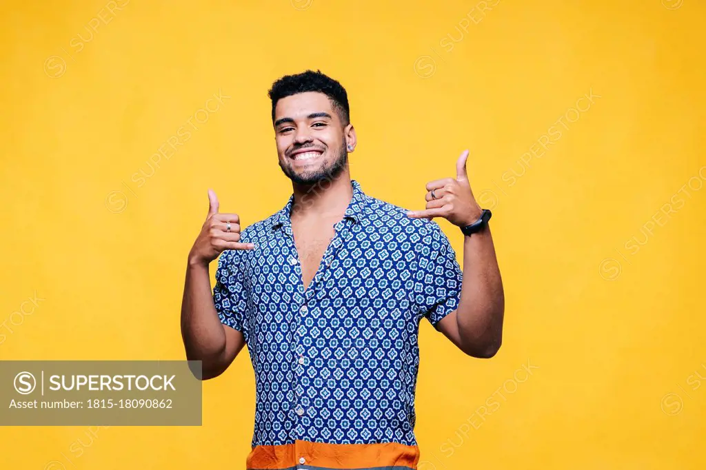 Smiling handsome man gesturing against yellow background