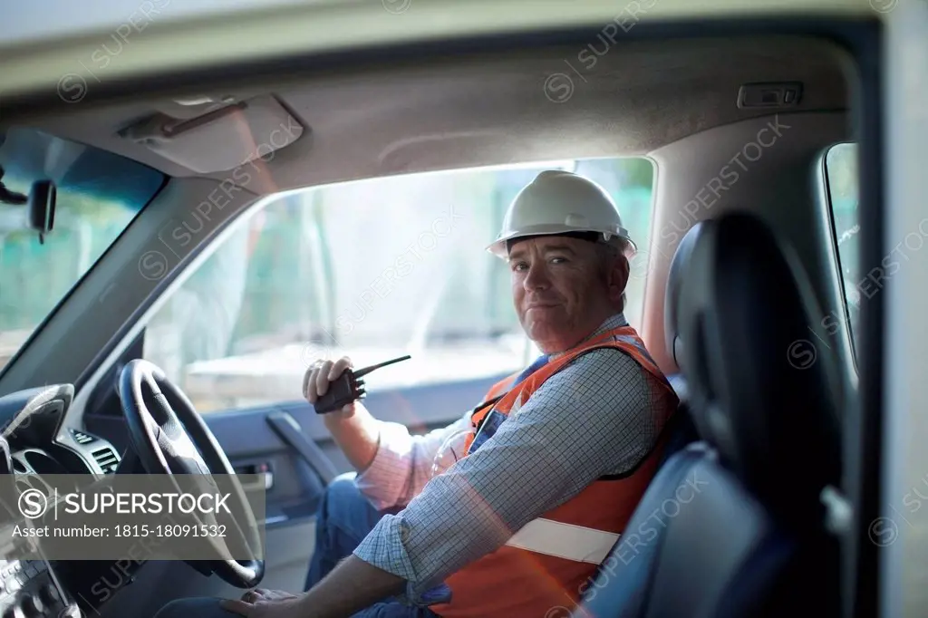 Male architect with walkie talkie sitting in truck at construction site