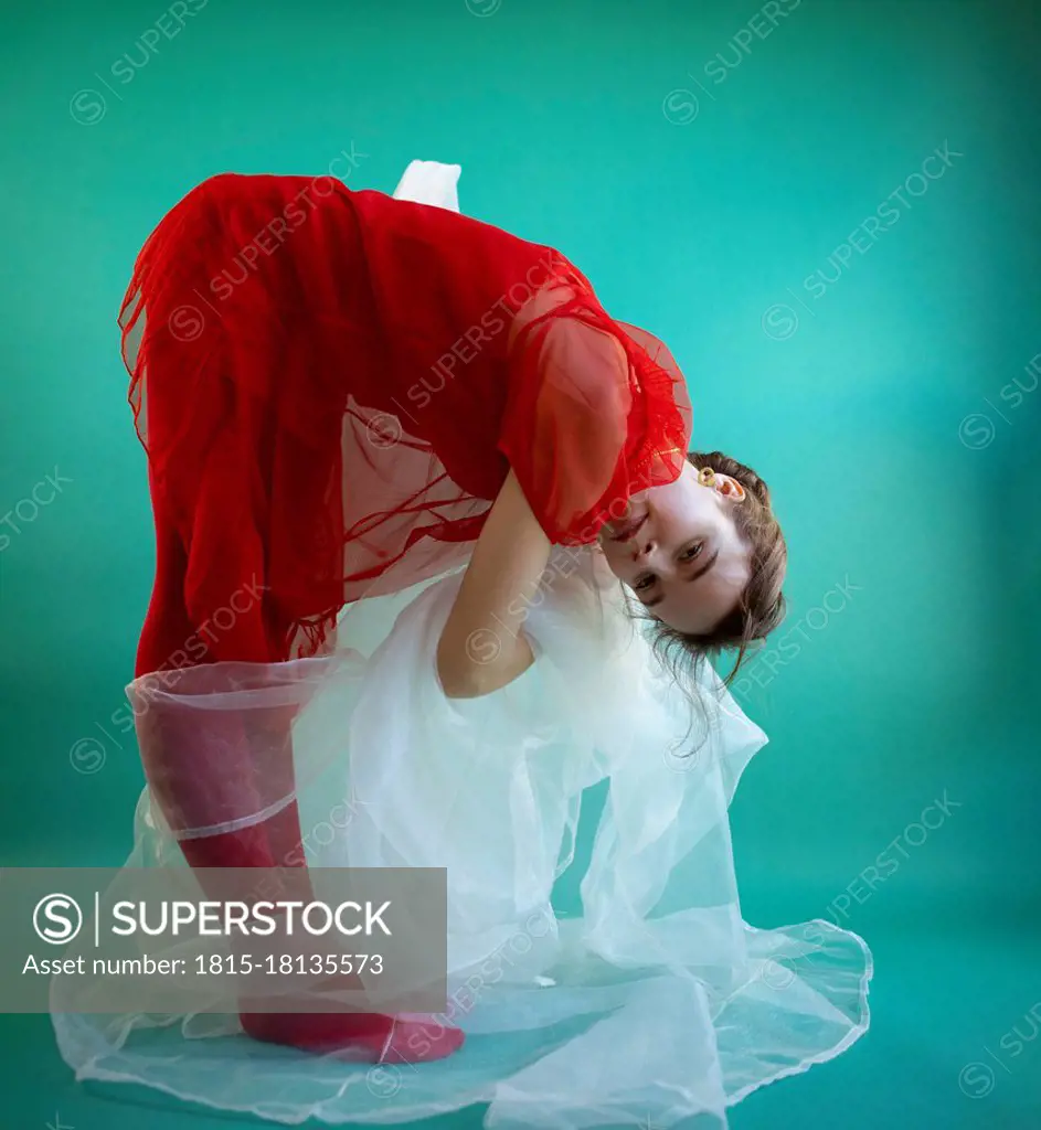 Female dancer bending against turquoise background